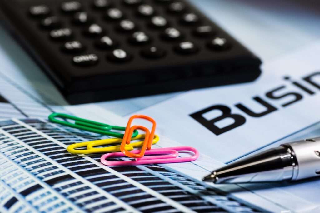 Colorful paper clips, calculator, and pen on a business document - Age Calculator BC concept