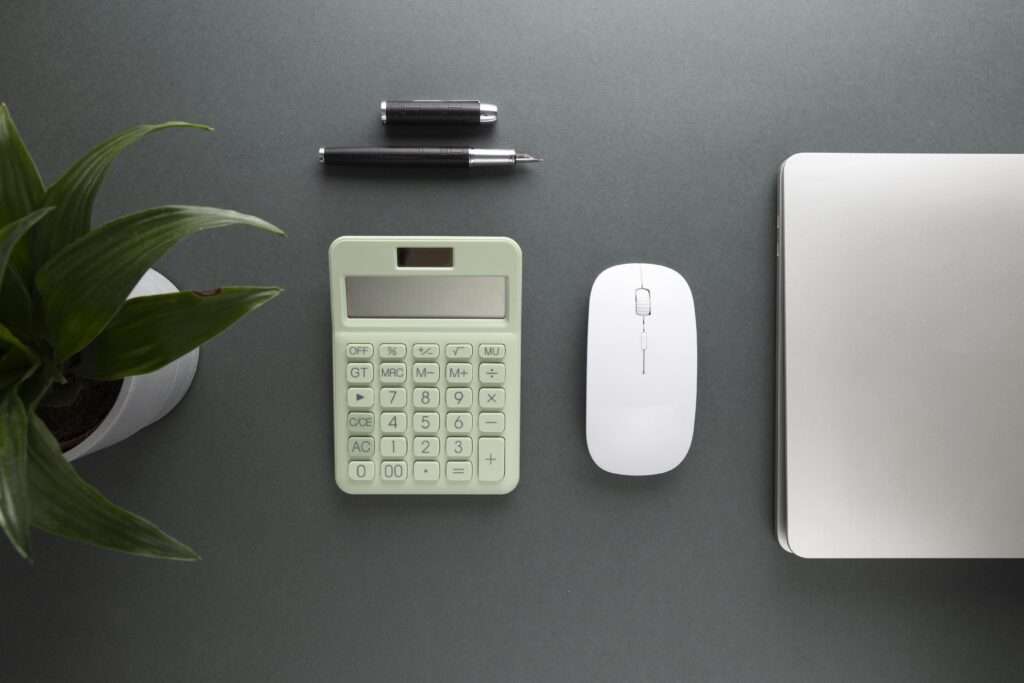 Minimalist desk setup with calculator, pen, mouse, and laptop for Age Calculator NMK